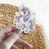A cute, stylized white unicorn with a rainbow mane and tail, prancing with stars.