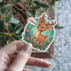 A cute cartoon fawn with big green eyes and antlers is depicted in a forest setting with flowers, saying 'Talking'.