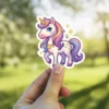 A cute, white unicorn with a golden horn, blue eyes, and a rainbow-colored mane and tail, adorned with a star pendant.