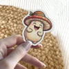 A cute, cheerful mushroom character sticker featuring a red and orange spotted cap with a green leaf, and a creamy white body with rosy cheeks, smiling broadly.