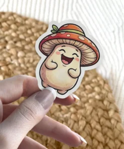 A cute, cheerful mushroom character sticker featuring a red and orange spotted cap with a green leaf, and a creamy white body with rosy cheeks, smiling broadly.