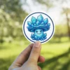A cartoon mushroom with a mischievous face, covered in glowing blue crystals, framed by a blue circle.