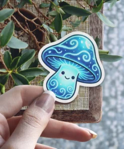 A cute, smiling blue mushroom with swirling patterns on its cap and stem is held by a hand.