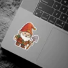 A friendly cartoon garden gnome wearing a red hat and green tunic, holding a small gray shovel, ready for gardening adventures.