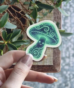 A vibrant illustration of a glowing blue-green mushroom sticker with a smiling face and intricate swirling patterns, radiating a magical aura.
