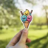 A cute kawaii-style sticker of an ice cream cone with three colorful, happy scoops, each with a funny cartoon face.