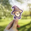 A kawaii mushroom character wearing a starry wizard hat and robe waves happily.