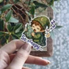 A whimsical sticker featuring a sleepy elf child in a star-patterned nightcap hugging a pillow, with 