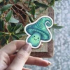 A cute, smiling mushroom with a wizard-like hat in shades of teal and green.