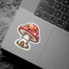 A cheerful mushroom house sticker with a smiling face, red cap, and white spots.