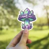 A vibrant sticker features a stylized mushroom composed entirely of sparkling purple and green crystals.