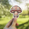 A mushroom sticker with folk art inspired patterns in red, blue, and yellow.
