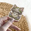 A grumpy mushroom character sticker with crystal growths and moss on its cap and base.