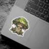 A vinyl sticker depicts a grumpy mushroom with a face, mossy cap, and wood-like stem, surrounded by grass.
