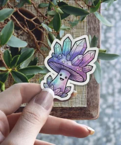 A cute, smiling mushroom sticker adorned with an iridescent cap of purple, pink, and teal colored crystals.