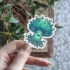A whimsical green mushroom character with spiky protrusions on its cap and swirling tentacles below, featuring a cheerful, smiling face.