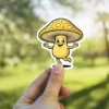 A cartoon yellow mushroom character with a wide smile and outstretched arms, rendered in a retro comic style, is shown against a blurred green background.
