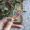 A colorful cartoon ice cream cone sticker with three happy-faced scoops in teal, pink, and yellow.