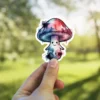 A whimsical watercolor mushroom character with a happy face and vibrant blue, pink, and purple hues.