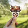 A unique steampunk-inspired mushroom sticker featuring metallic textures, gears, and a small circular window.