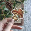 A whimsical steampunk mushroom character adorned with gears, a monocle, and a mustache, presented as a vinyl sticker.