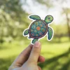 A vibrantly colored, stylized green sea turtle sticker featuring an intricately patterned shell with floral and marine elements.