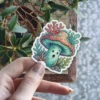 A whimsical sticker of a surprised-looking mushroom character adorned with coral and sea plants.