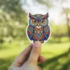 A sticker featuring a colorful owl with tribal-inspired patterns on its feathers and wings.