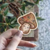 A trippy mushroom sticker featuring multiple eyes on the cap and a sleeping face on the stem.