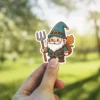 A cute cartoon farmer gnome with a white beard holds a pitchfork and carries a backpack filled with autumn leaves.