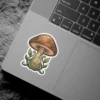 A decorative sticker featuring an illustrated mushroom with a red cap and green leafy swirls, giving a mystical forest vibe.