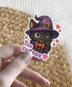 A winking black cat wearing a purple witch hat and a bow tie, with the words 'Too cute' beside it, surrounded by small pink hearts.