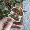 A sticker depicting an anthropomorphic mushroom with a wise, bearded face and a brown cap with orange spots.