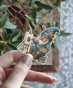 An artistic gnome with a blue hat, beard, and palette paints a ladybug on an easel.