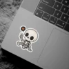 A cute cartoon skeleton giving a peace sign with a heart in a speech bubble, black eyes, white bones, vinyl sticker.