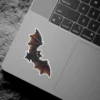 Chibi style black bat, golden yellow eyes, orange wing gradients, detailed digital art, vinyl sticker.
