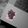 A charming winking black cat wearing a purple witch hat and cloak, with pink hearts and the phrase 'Too cuteee' around it, making for an adorable vinyl sticker.