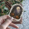 Ethereal ghost, bright full moon, grinning jack-o'-lanterns, gravestones, spooky trees, ornate border vinyl sticker.