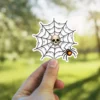 Skull, dew-covered spider web, glowing orange spider, spooky gothic aesthetic illustration, vinyl sticker.