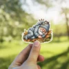 A sleeping gnome in striped pajamas rests on autumn leaves with a bird on his hat.