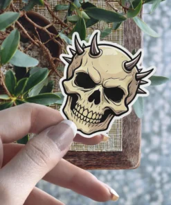 Tan skull, dark horns, black recessed eye sockets, bold line art, vinyl sticker.