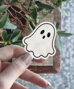 White ghost sticker, classic wavy shape, three black oval eyes, bold black outline, fun spooky vinyl sticker.