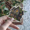 Haunted gothic stone mansion, mossy roof, glowing orange windows, boarded doors, spooky illustration, vinyl sticker.