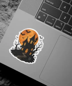 A dark, eerie haunted mansion sits on a hill under a bright orange full moon with bats flying around. Vinyl sticker.