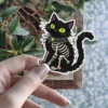 Black cat, glowing green eyes, web collar, skeleton ribs, spooky aesthetic, vinyl sticker
