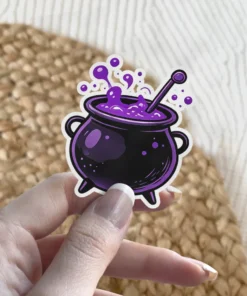 Detailed black cauldron holds vibrant purple bubbling potion, complete with a stirring stick and a crisp white outline vinyl sticker.