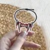 Illustrated vampire fangs dripping blood on black cord choker necklace, die cut vinyl sticker.