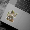 A sticker featuring a detailed illustration of a garden gnome wearing a green hat adorned with flowers and a small compass, holding onto a grape vine.