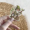 A charming vinyl sticker depicts a gnome with a long white beard and a green hat adorned with flowers. He is reaching for a vine while standing on wooden crates.