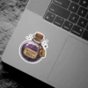 Stylized illustration of a clear bottle filled with sparkling purple 'Witches Brew' potion, cork stopper, crescent moon charm, vinyl sticker.